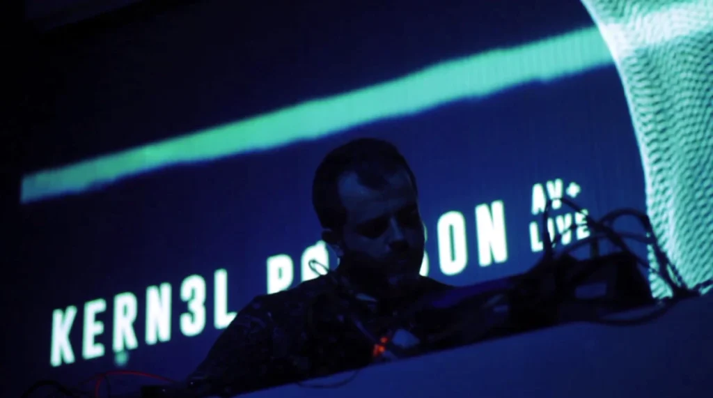 Close-up of Víctor Martínez performing as K3rn3l Pøissøn at Celobert Festival, with audiovisual projections behind him.